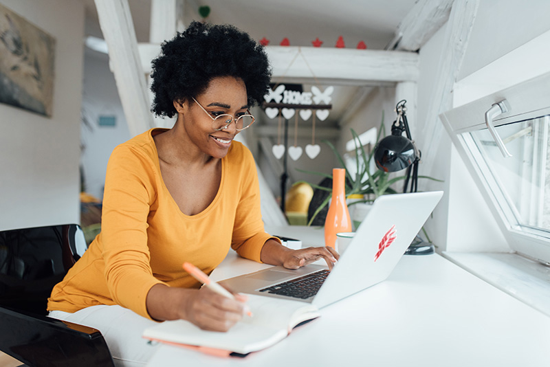 An accountant uses a laptop and ledger to reconcile accounts