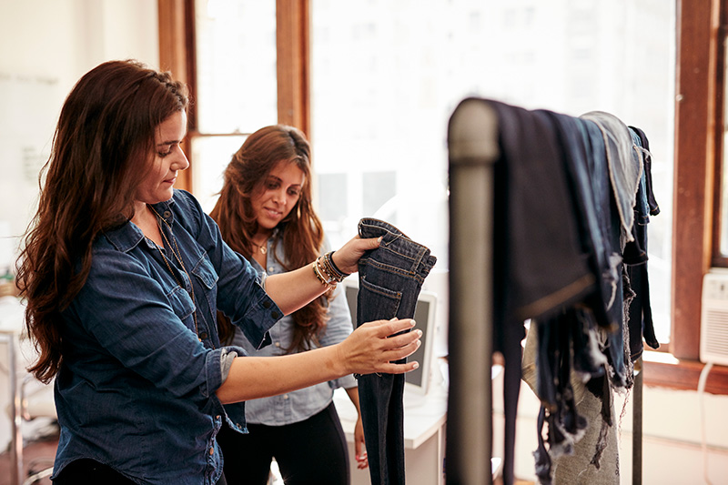 A business manager talks with a colleague as they look over clothing inventory
