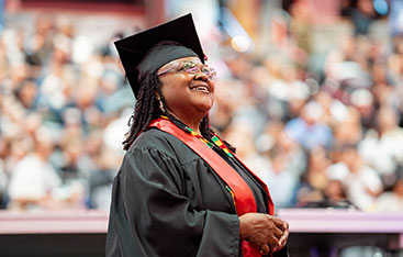 A happy bachelor's degree graduate look up into the crowd at a University of Phoenix  commencement ceremony