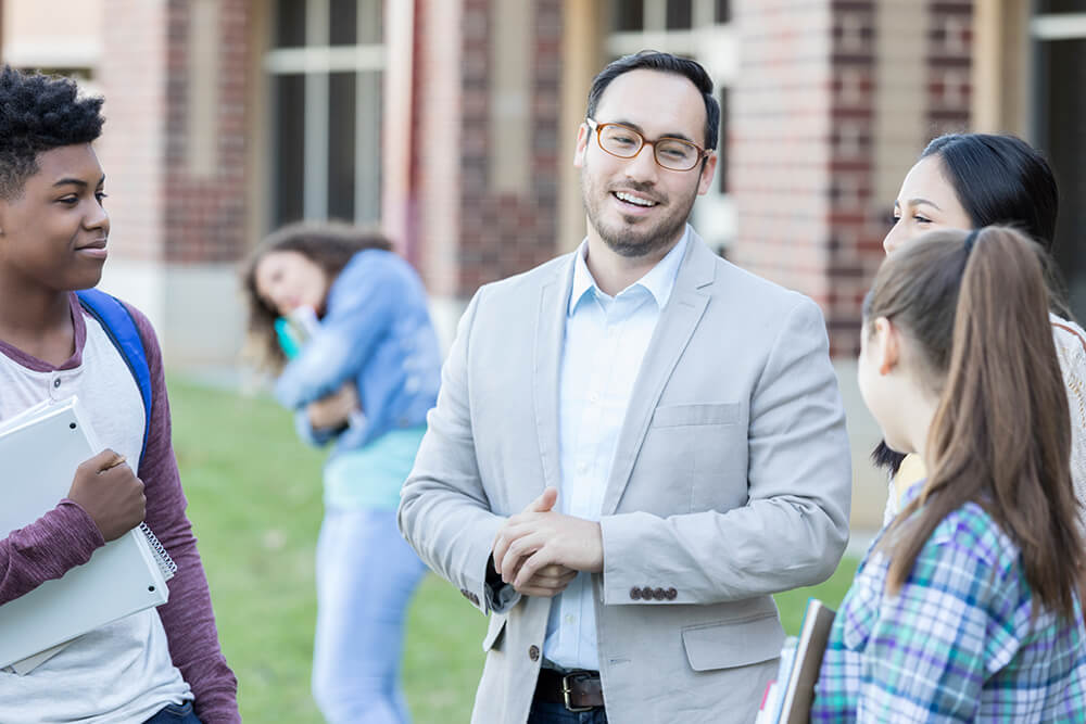 A school principal chats with students outside