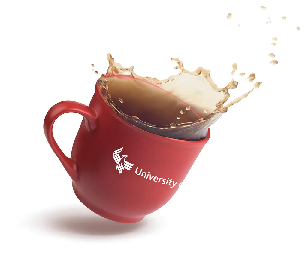 Red University of Phoenix branded mug with handle to the left spilling coffee droplets in the air while falling at a 45 degree angle.