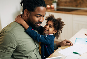 A person holding a young child at a desk illustrates that beginning a career can be initiated at any stage in life.