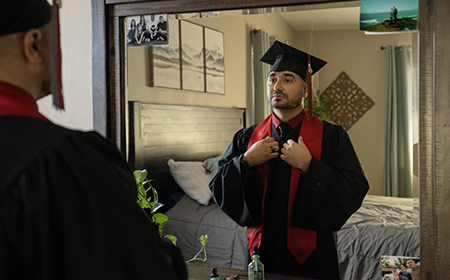 Commencement ready University of Phoenix graduate checks look in mirror