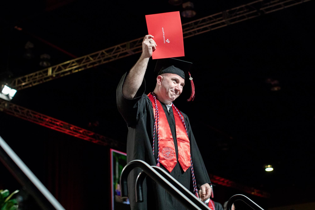 University of Phoenix student accepting their degree at commencement.