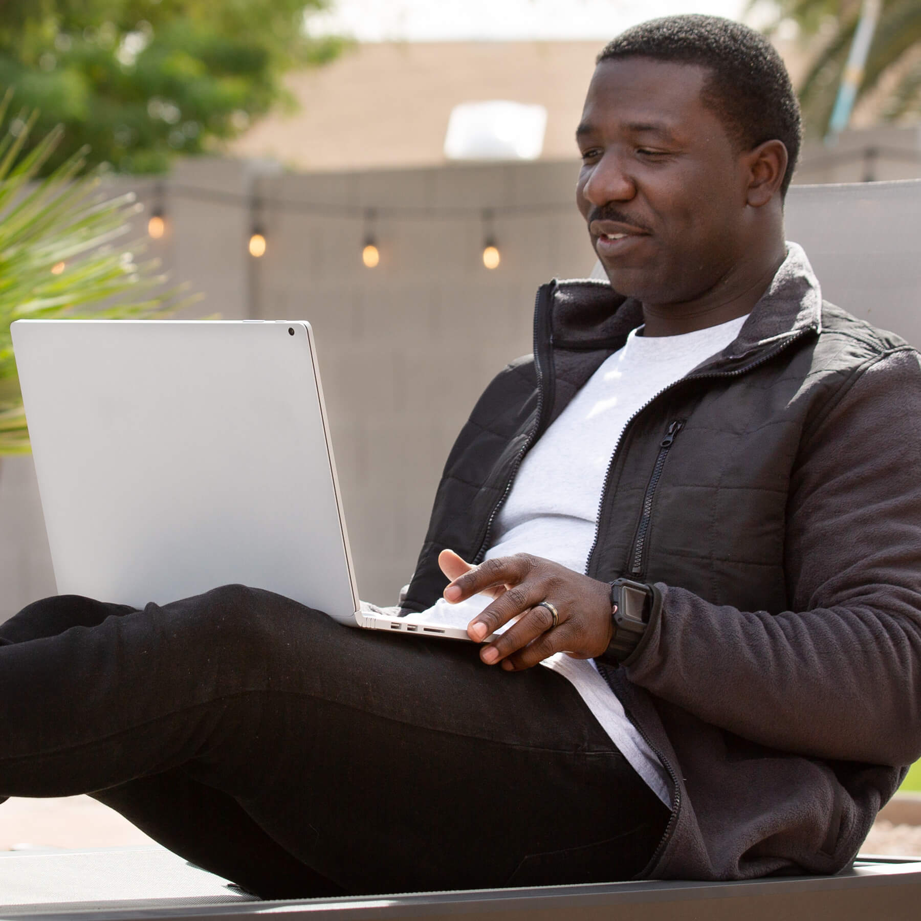 Jahmar Robinson studying on his laptop, outside on a patio