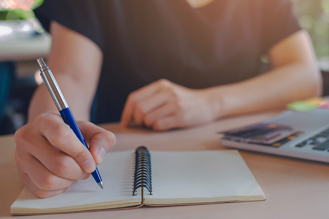 Business woman hand is writing on a notepad with a pen.Web banner.