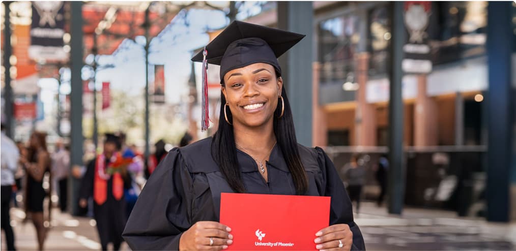 A graduate wearing a cap and gown and holding their diploma