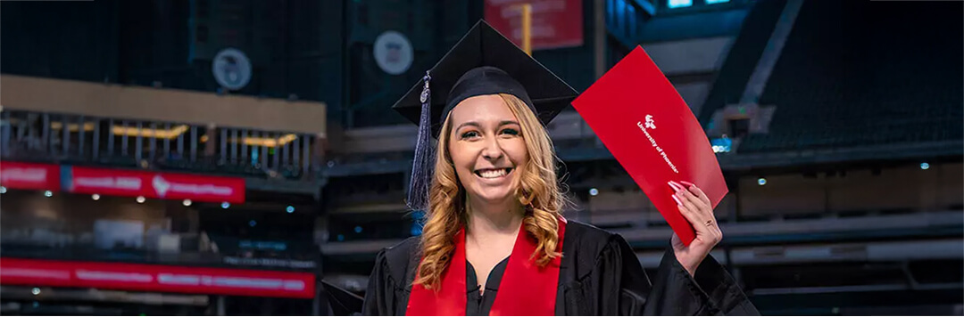 graduate proudly holding up diploma