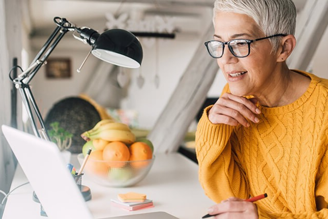 Woman looking at her laptop to register for a webinar