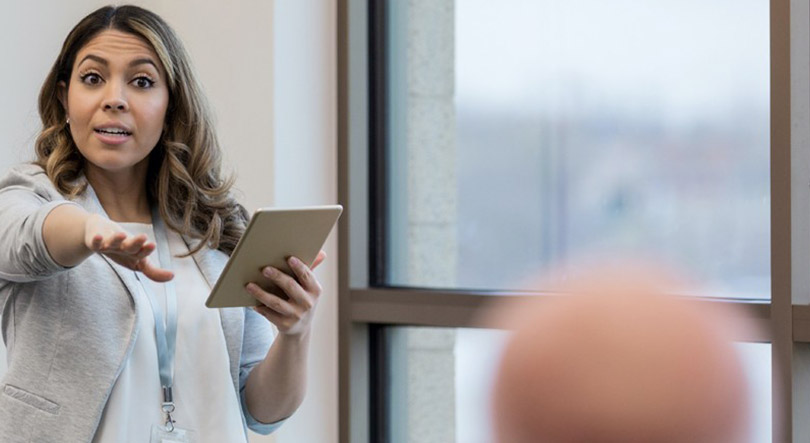 A confident woman in a business suit gives a presentation on earning an online bachelor’s degree