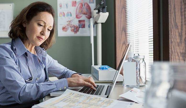 A professional with a Bachelor of Science in Health Administration works on a laptop to help improve patient care