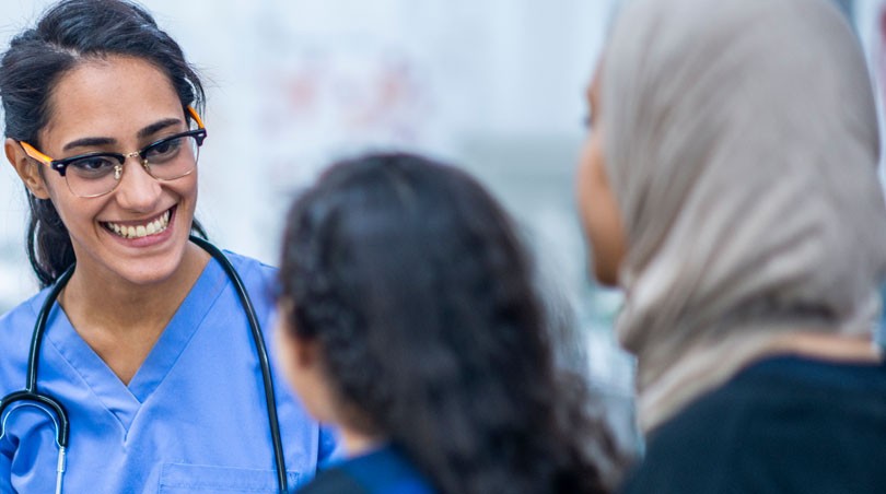 A RN to Bachelor of Science in Nursing student happily talks to a patient 