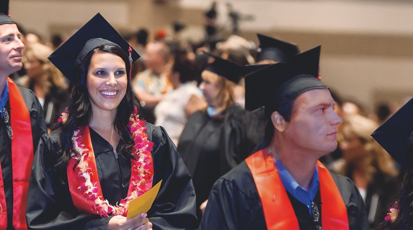 University of Phoenix graduate in cap and gown smiles during the commencement ceremony