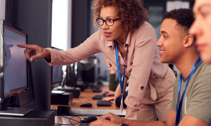 university of phoenix faculty member engaging with students in computer lab