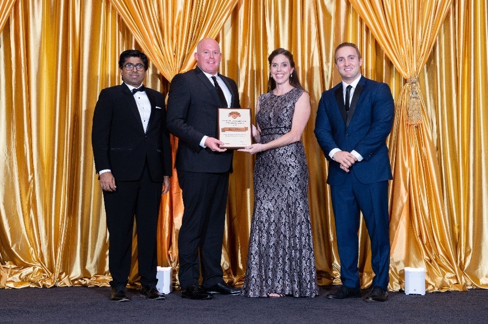 Four people accepting the 2019 Academic Circle of Excellence Award in front of a gold drape