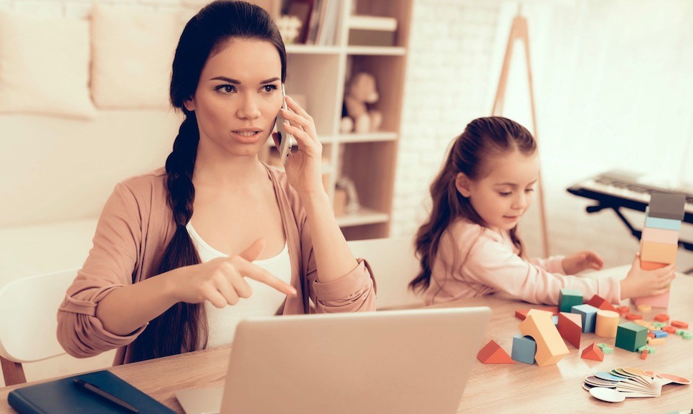 Adult student with laptop and child playing nearby