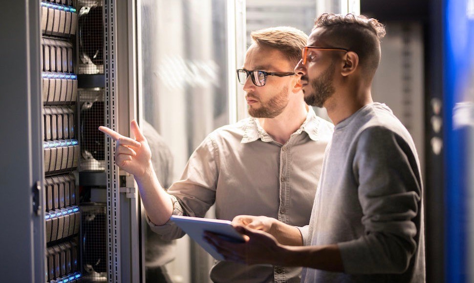 Two information technology professionals examine equipment in a server room