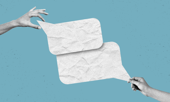 Two hands holding paper cutouts in the shape of text bubbles, papers are touching in the center of the frame.