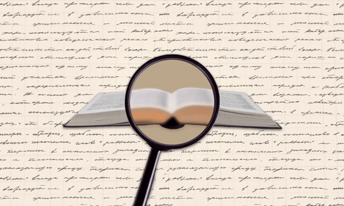 An magnifying glass in front of an open book with scripted text in the background.