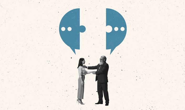 A man and a woman shown in the center of the frame facing one another and shaking hands.