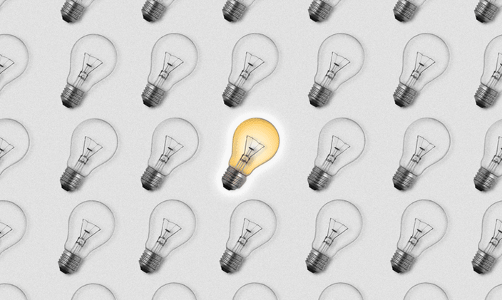 Black and white lightbulbs fill the frame, with a single yellow bulb in the middle of the frame.