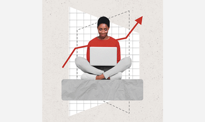 Woman sitting cross-legged with an open laptop in her lap and a red and white chart behind her.