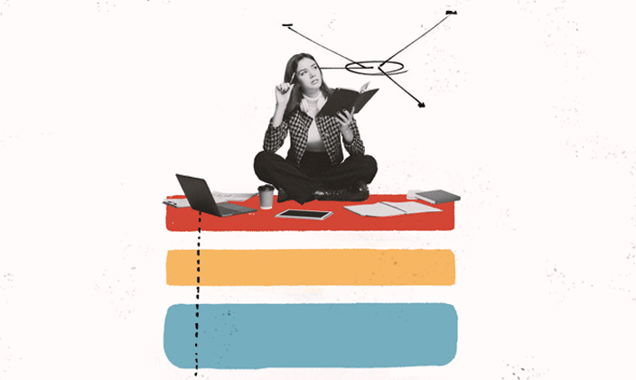 Woman sitting cross-legged with an open book and an open laptop next to her.