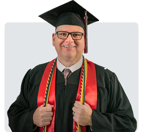 Graduate in academic regalia smiles and poses to promote alumni scholarship opportunities.