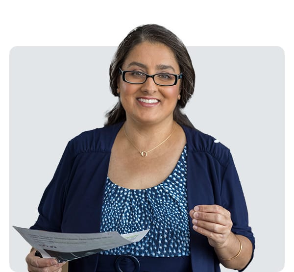 Staff member holding a paper and smiling, representing tuition assistance opportunities.