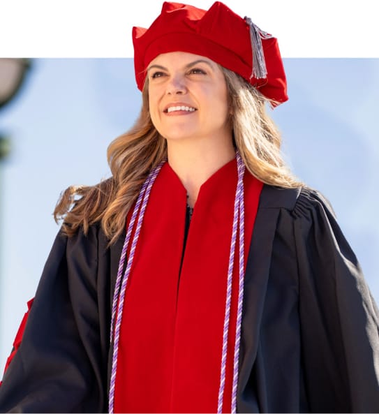 Doctoral graduate in cap and gown celebrates completing an online DBA program, highlighting the easy application process.