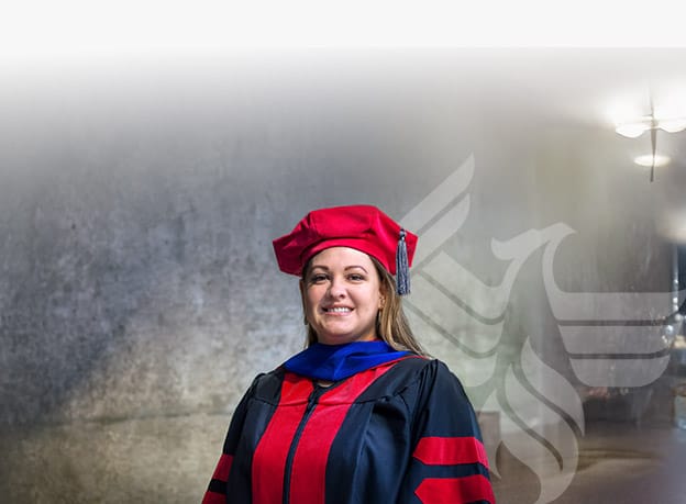 A smiling University of Phoenix DBA graduate in their graduation attire
