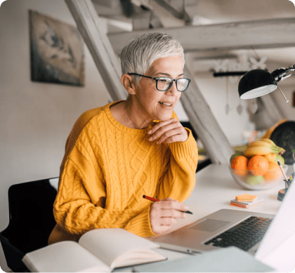 A student smiles while reviewing research notes on a laptop for an online DBA literature review.