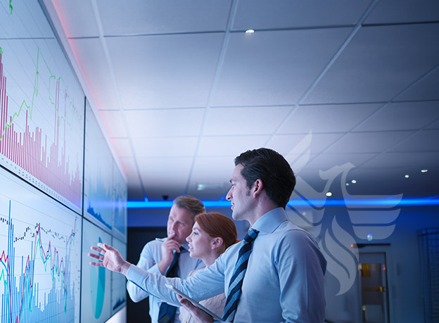 A team of three people reviewing digital graphs on a wall