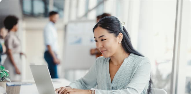 Business student smiling and working on a laptop