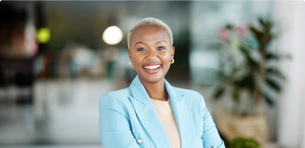  A confident smiling woman in a blazer symbolizes the flexibility of taking online classes while being a professional.