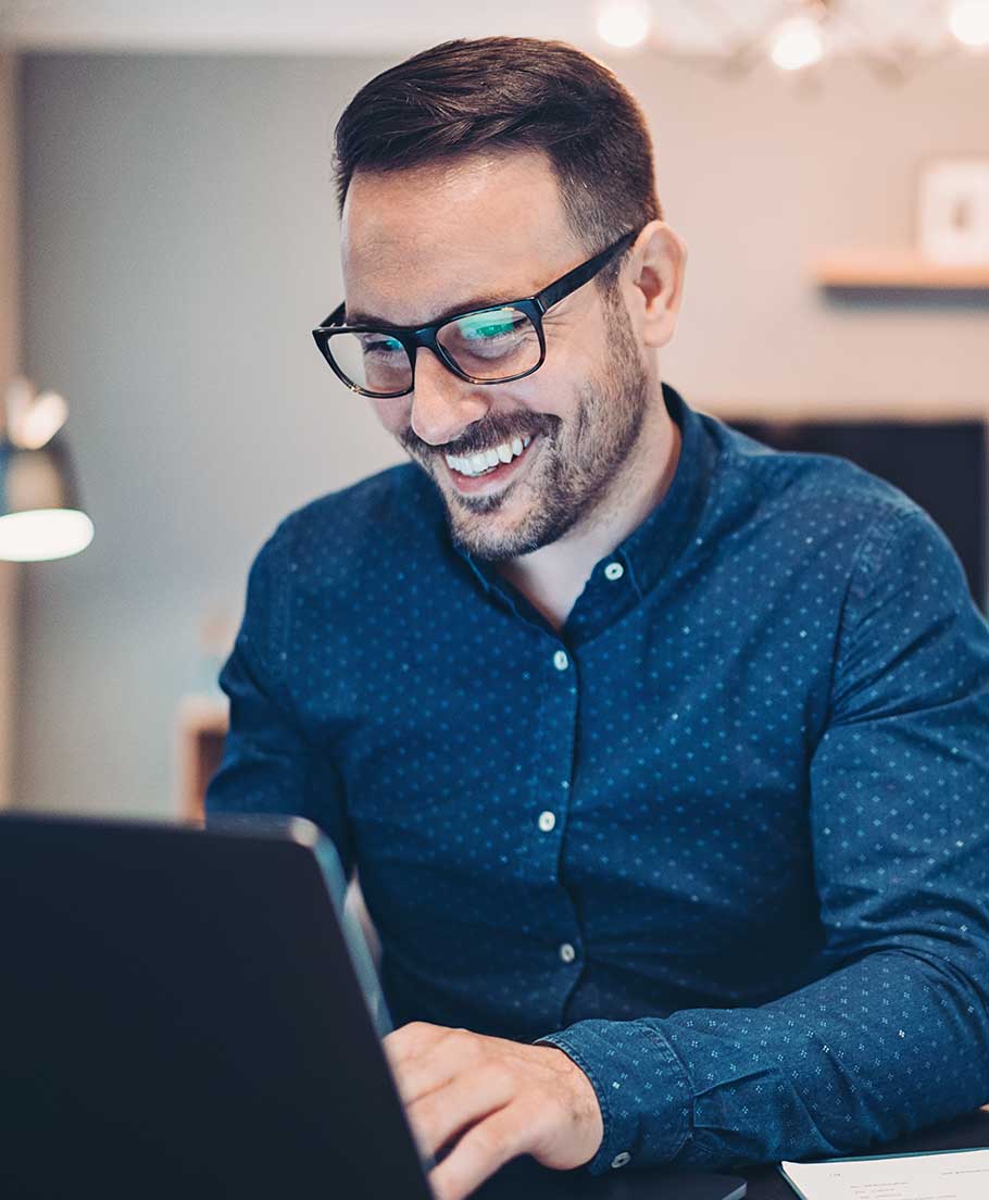 Man smiling while working on a laptop