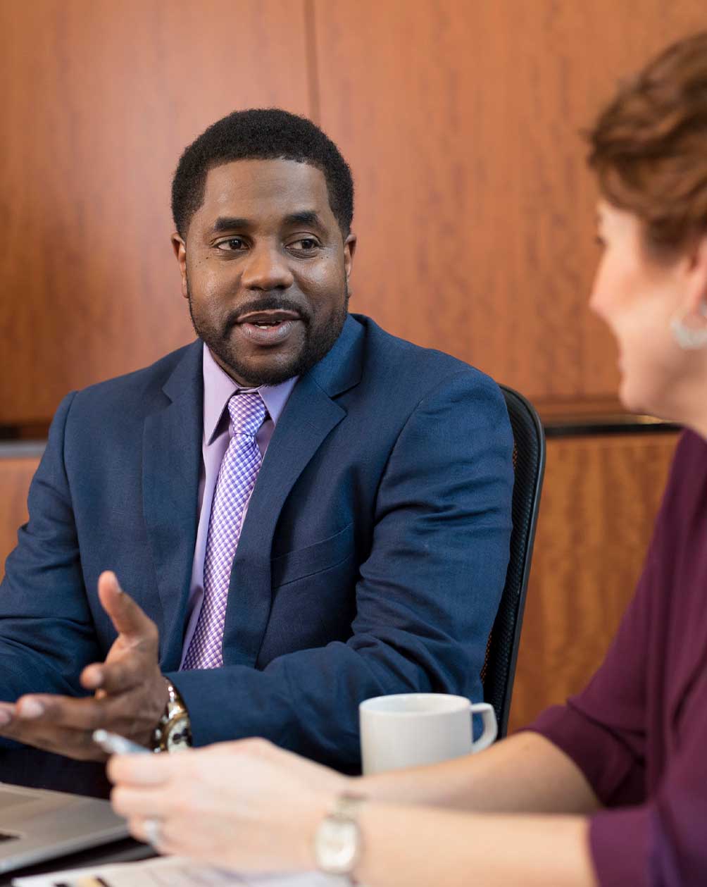 Black man in a suit talking with a colleague 