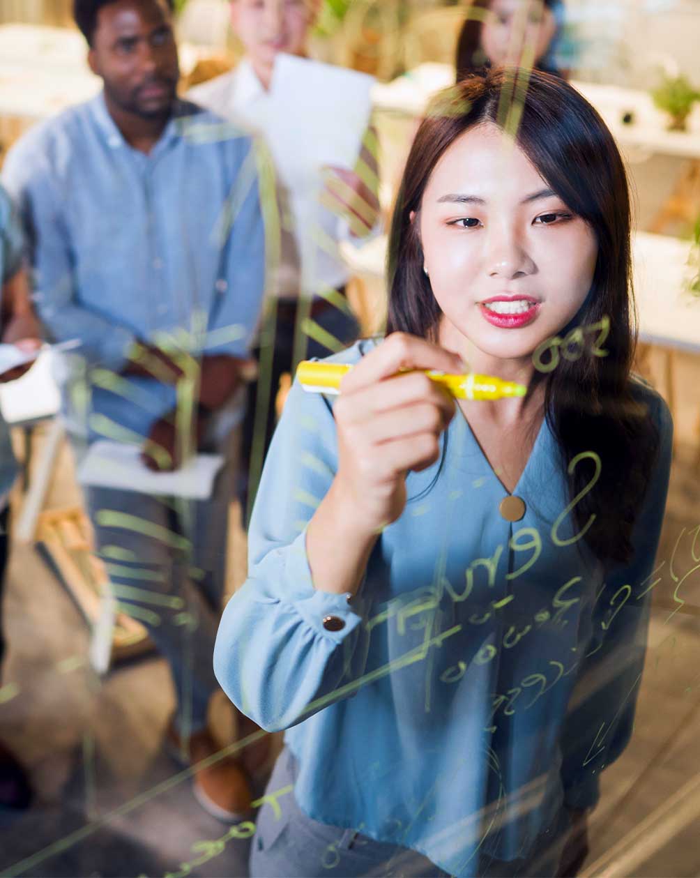 Women writing on a glass idea board 