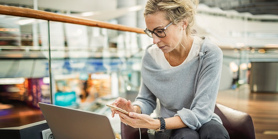 Woman looking at smartphone and laptop computer