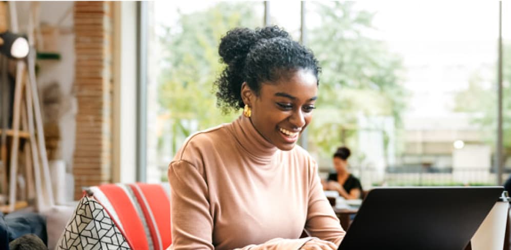 Smiling woman working on a laptop in a brightly lit modern office
