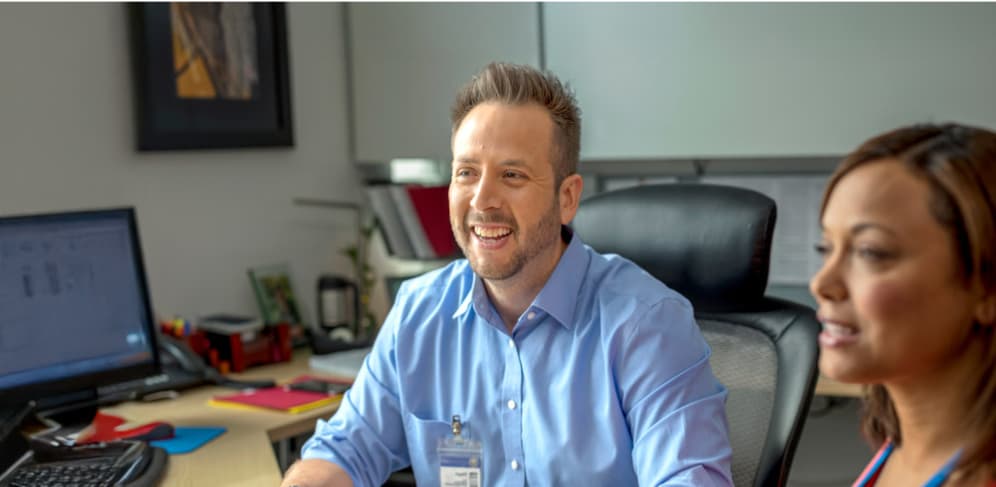 Two colleagues smiling while collaborating in an office