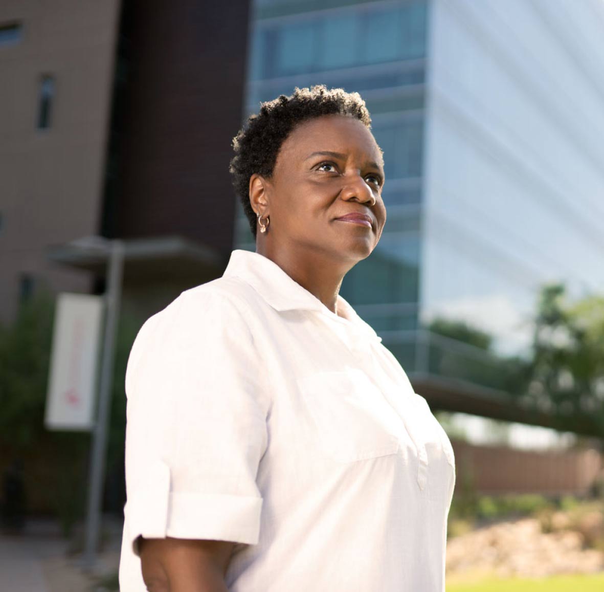 Faculty member proudly standing in front of an office building