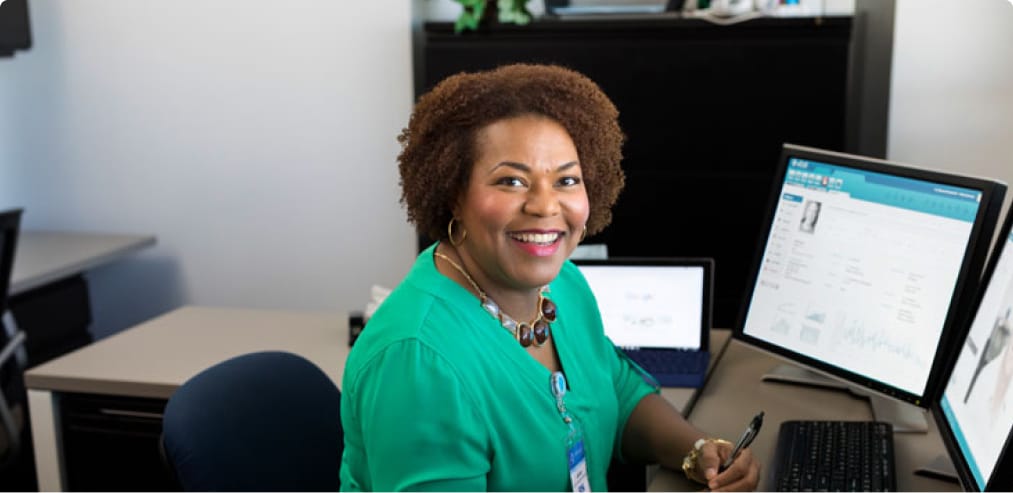 A nursing student smiling at their desk 