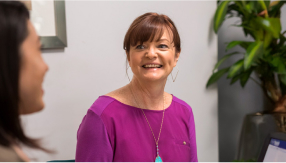  A confident, smiling alumna works with a colleague in an office, symbolizing University of Phoenix MSP education is relevant and practical.