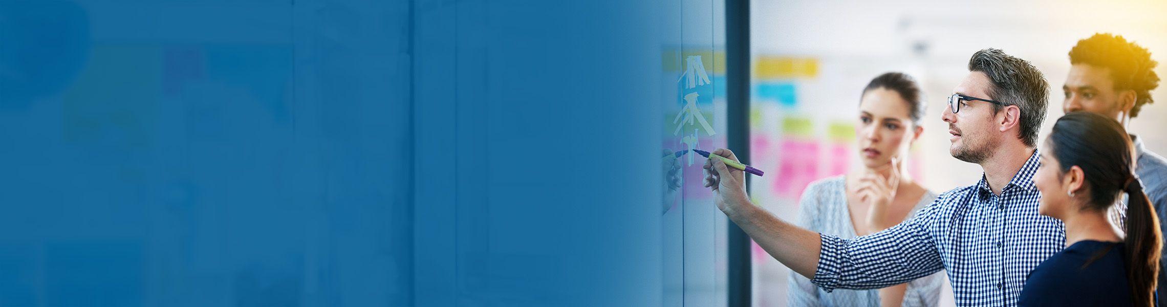 A professional writing on a sticky note while his colleagues are looking at him.