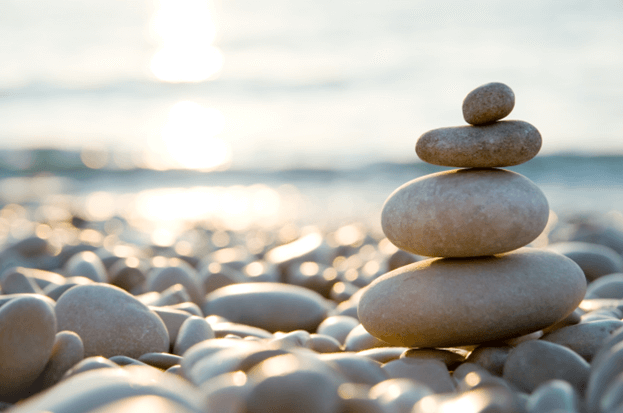 A stack of smooth stones next to a peaceful body of water