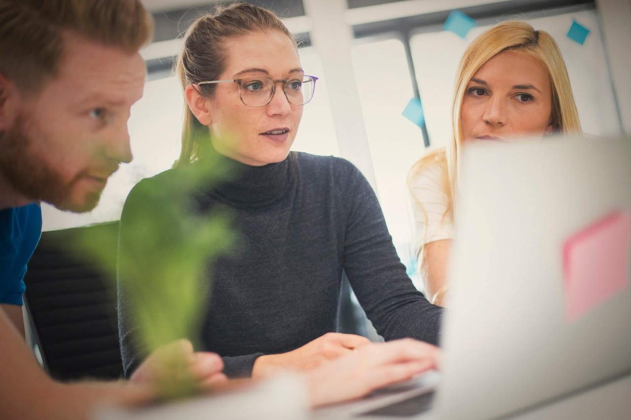 Photo of three people looking at a computer