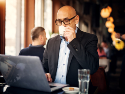 Man sitting looking at computer in a coffee shop drinking coffee