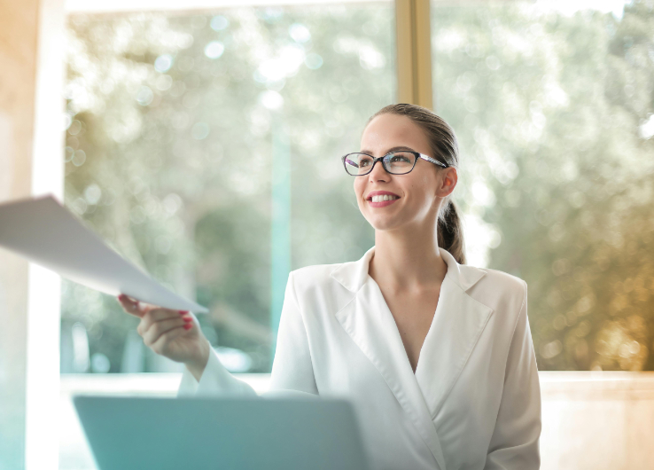 Photo of a woman at work handing papers to someone and smiling