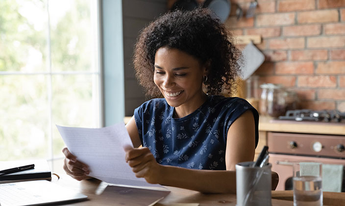 A first-year student smiles as she reviews an academic paper